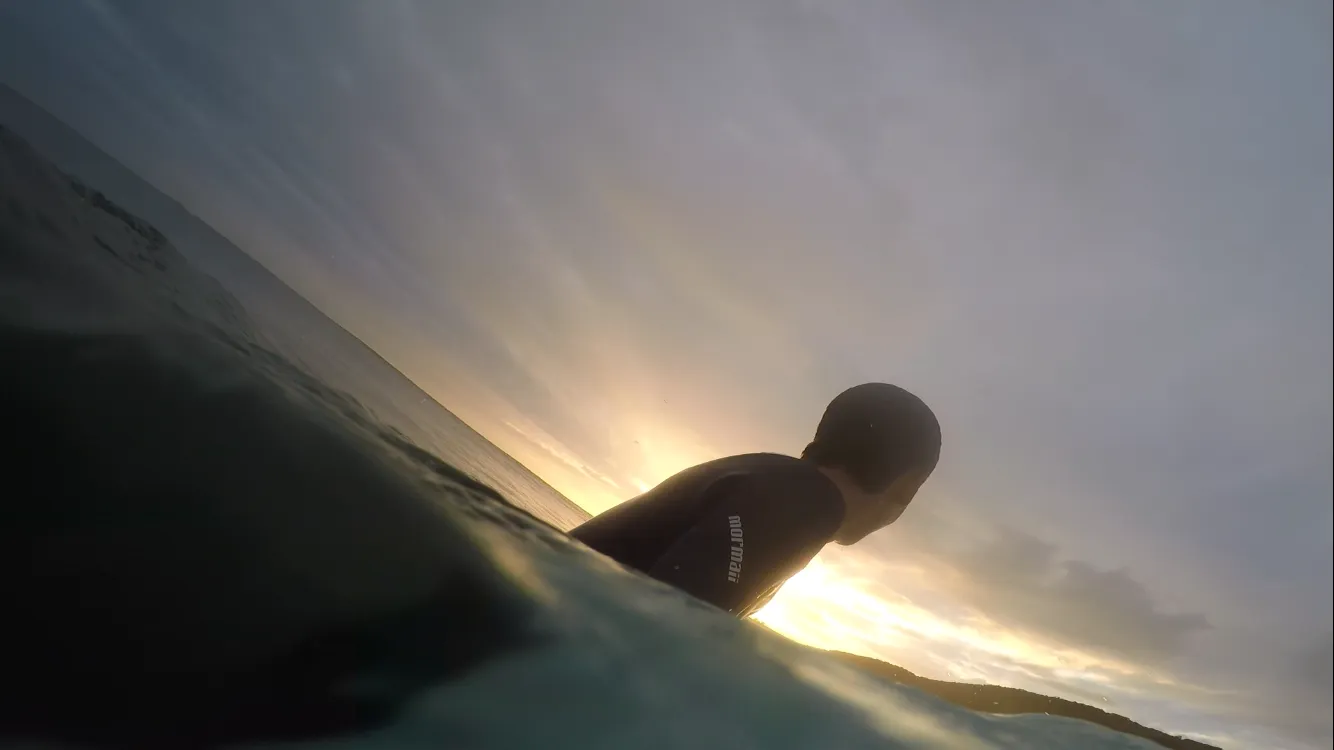 Illustration of a surfer sitting on a board at sunrise